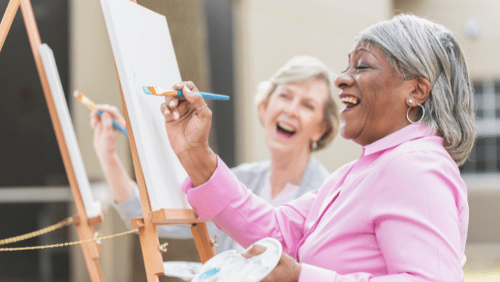 a couple of senior ladies painting and smiling each other